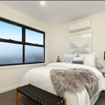 Split system air conditioner above a bed in a bedroom
