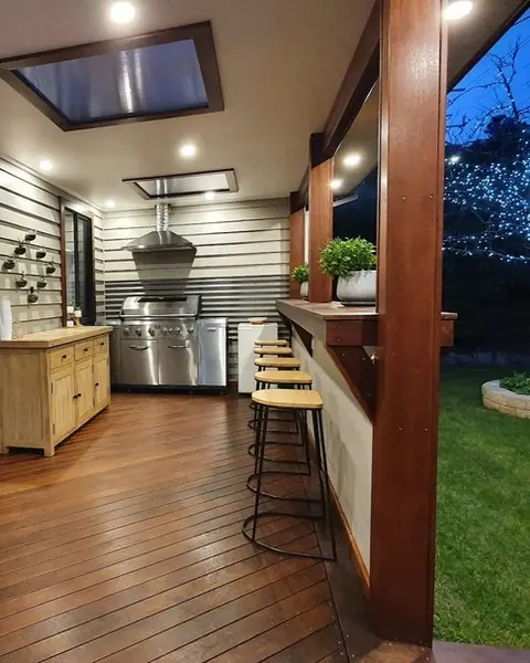 Outdoor kitchen and bar with downlights in the alfresco ceiling at night