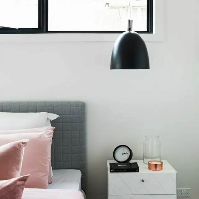 Black dome pendant light hanging beside a bed