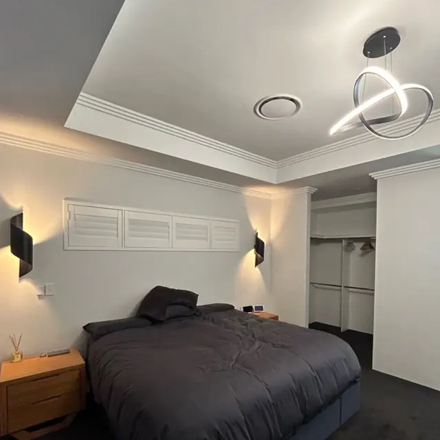 Bedroom with black wall lights either side of the bed and a ring LED pendant above