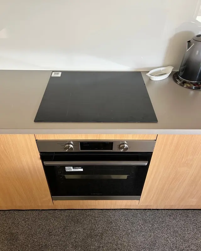 Black induction cooktop above a built-in wall oven