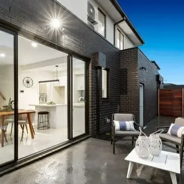 Rear courtyard with exterior wall lights on a dark brick wall