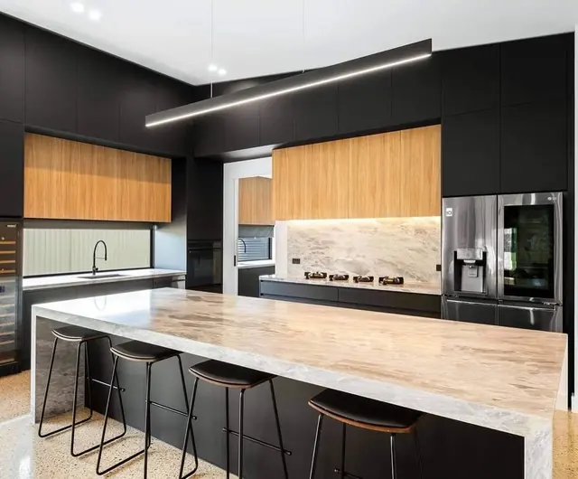 Linear LED pendant light above a stone kitchen island in a dark-cabinet kitchen