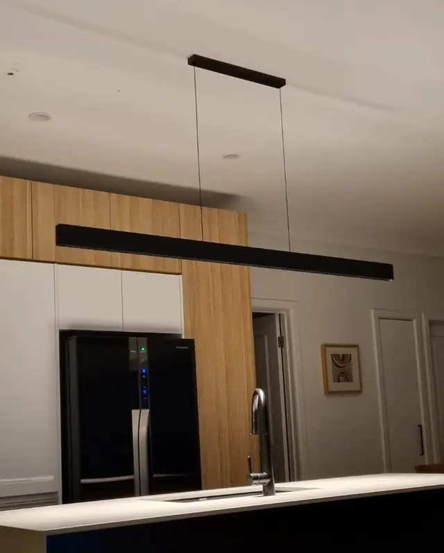 Black linear pendant light above a kitchen island