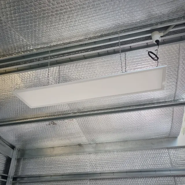Suspended LED panel light hanging below a foil-insulated ceiling