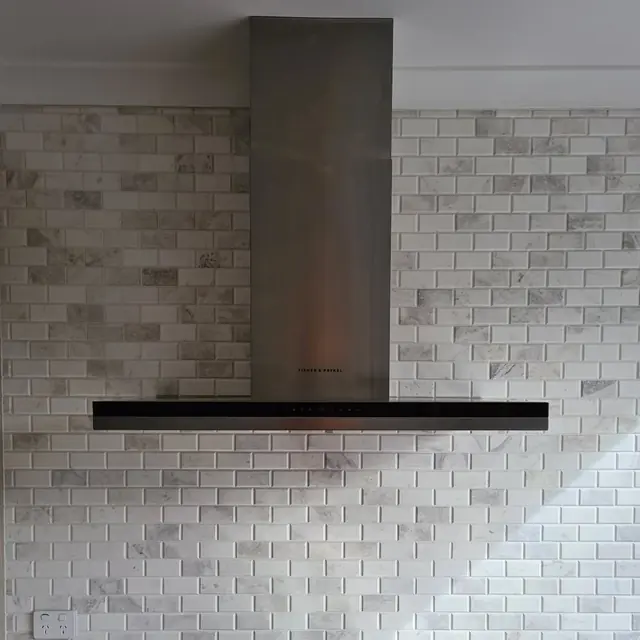 Stainless steel rangehood installed on a tiled kitchen wall