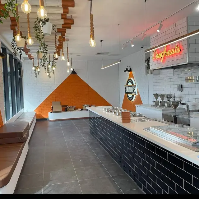 Shop interior with exposed-bulb pendants and track lighting above a long counter