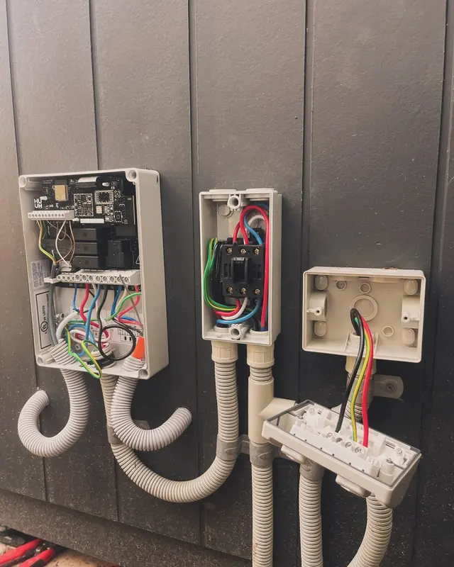 Open weatherproof enclosures on an exterior wall with controller wiring and conduit