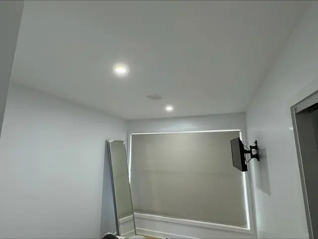 Wall-mounted TV bracket and recessed downlights in a room